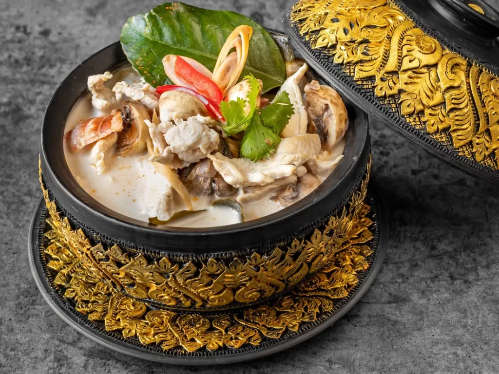 Close-up of tom kha gai with chicken, mushrooms and Thai herbs at Thai Food Near Me NYC